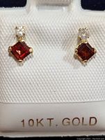 Front view of pair of 10K gold earrings with square garnet stones and small diamond accents.