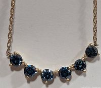 Close-up of six prong-set blue diamonds on yellow gold bar