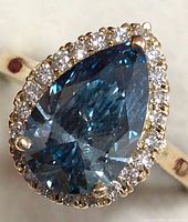 Top-down close-up of pear-shaped fancy blue center diamond with surrounding round accents