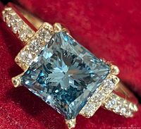 Close-up of central princess-cut blue diamond and surrounding pave diamonds