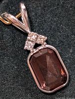Close-up view of 14K gold pendant featuring a large rectangular faceted reddish-brown stone and small round white diamonds arranged in a cluster above it.
