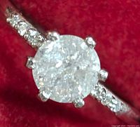 Close-up view of center round diamond and shoulder stones against red background
