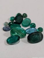 Close-up of multiple loose emerald gemstones showing various sizes and shapes.