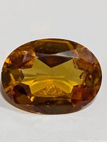 Front view of the oval faceted yellow-brown gemstone showing its clarity and color hues.
