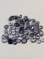 Loose genuine iolite gemstones assorted sizes and shapes on a white background.