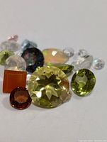 Photo of multiple loose gemstones in various colors and shapes, showing the lot contents.
