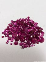 Pile of loose round faceted rubies on white background