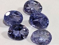 Close-up of five loose oval faceted Tanzanite gemstones showing color and clarity.
