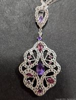 Front view of silver pendant showing amethyst and cubic zirconia stones in intricate filigree setting.