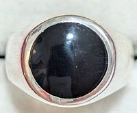 Close-up of front top view showing polished black onyx stone in silver bezel setting on ring band.