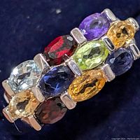 Close-up angled view showing the multi-colored faceted oval gemstones set in silver.