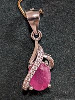 Close-up photo showing the front view of the silver pendant with ruby and cubic zirconia swirl design.