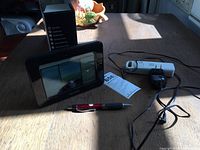 Photo of Acurite weather station digital display screen, sensors and power adapter on wooden table with pen for scale, box visible behind.