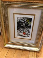 Framed photograph showing angel statue holding tomato in double matted gold and white frame