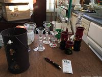 Photo showing assorted candle holders on countertop including glass, crystal, wood, and metal pieces, plus broken frosted votive and the base of floating candle holder.