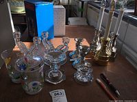 Wide photo showing all candlestick holders and light-up candles arranged on a table in natural light, displaying various materials including glass, pewter, plastic, and metal.