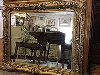 Full view of rectangular wall mirror with ornate gold painted gesso frame showing intricate detailed corners and edges, reflective surface visible.
