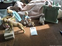 Wide photo showing the collection of Grandeur Noel figurines arranged on a surface including children with dogs and a decorative mantle piece.
