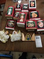 Photo showing the 12 boxed Hallmark religious themed ornaments, 2 angel figurines, and one wooden nativity ornament.