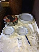 Overall view of plates including floral patterned Sakura by Oneida small plates stacked and larger white plates with silver rim