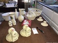 Wide shot of ceramic and decorative items including basket bowl, candle holders, shakers, vases on wood table