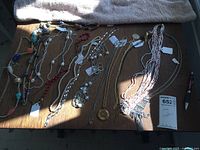 Multiple long costume necklaces laid out on wooden table in natural light showing stylistic variety and detail