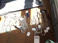 Photo showing eleven medium-length costume necklaces in a variety of bead styles and colors, displayed on a wooden surface with tags attached for length and identification.