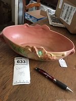 Roseville Poppy mold 338-10 console bowl pink glaze with green and brown painted flower detail on rim, alongside a pen and lot tag for scale.