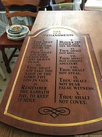 Photo of large wooden plaque featuring The Ten Commandments carved and partially highlighted with gold paint.