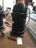 Full view of the black cylindrical theater can light showing size and shape next to pen for scale.