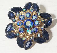 Top view of the star brooch showing layered blue and aurora borealis rhinestones set in a gold-tone metal base.