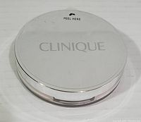 Top view of Clinique pressed powder compact, white lid with 'CLINIQUE' embossed.
