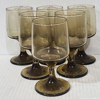 Front-facing view of six smokey brown goblets arranged tightly in two rows of three on a white surface against a plain white background.