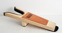 Side angle of wooden boot jack showing leather branded patch and U-shaped top end with dark trim.