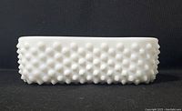 Side profile of white milk glass oblong dish showing hobnail pattern on exterior sides