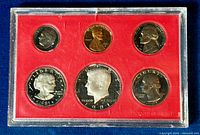 Front side of 1981 proof coin set showing heads of dime, penny, nickel, dollar, half dollar, and quarter in red-plastic holder.