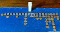 Coins arranged on blue cloth with white storage tube upright.