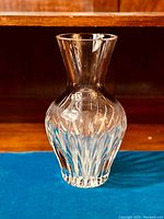Front view of clear lead crystal vase on blue velvet with wooden background