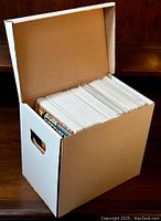 Open white short box filled with comic books stored upright in protective sleeves.