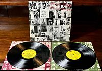 Photo showing the gatefold album cover with black and white collage art and the two vinyl records with yellow labels laid out.