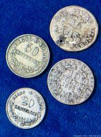 Top view of four antique Italian silver coins on blue background showing denominations and details.