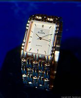 Close-up view of the Elgin wristwatch face and linked gold tone bracelet band, showing brand name, dial, and hands.