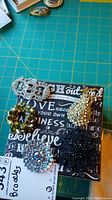 Photo of five assorted decorative rhinestone brooches on a black and white text background with green cutting mat below.