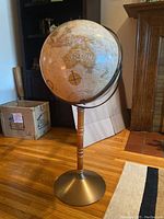 Full view of the freestanding globe showing wooden stand with metal base and map detail of Australia.