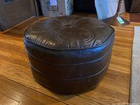 Side view of brown vinyl ottoman showing octagonal shape and horizontal stitch lines around the sides.