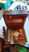 Open Bulova Accutron presentation box with watch, two bands, and logo pins