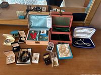 Overview of the lot showing multiple jewelry pieces displayed on a dresser, including boxes, necklaces, bracelets, earrings, rings, cufflinks, brooches, and pins.
