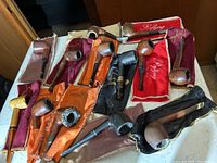 Overview of thirteen assorted briar pipes with colored cloth pouches
