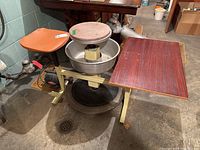 Front-angle view of complete pottery wheel assembly showing seat, wheel, basin, motor and side table