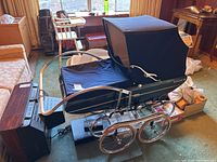 Side and angled view of vintage Pedigree Venus pram showing navy blue fabric with canopy, chrome frame, and large wheels.